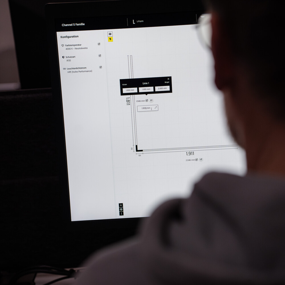 Person arbeitet an CAD-Planung mit genauen Maßen und Lichtspezifikationen für Leuchtenkonfiguration am Bildschirm.
