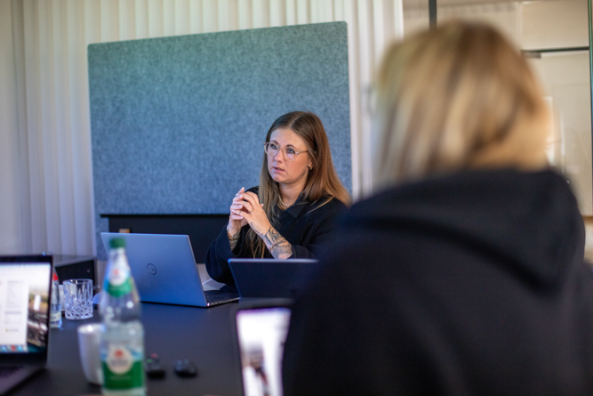 Frau analysiert konzentriert Daten an Laptop in modernem Büro, Besprechung im digitalen Arbeitsumfeld.