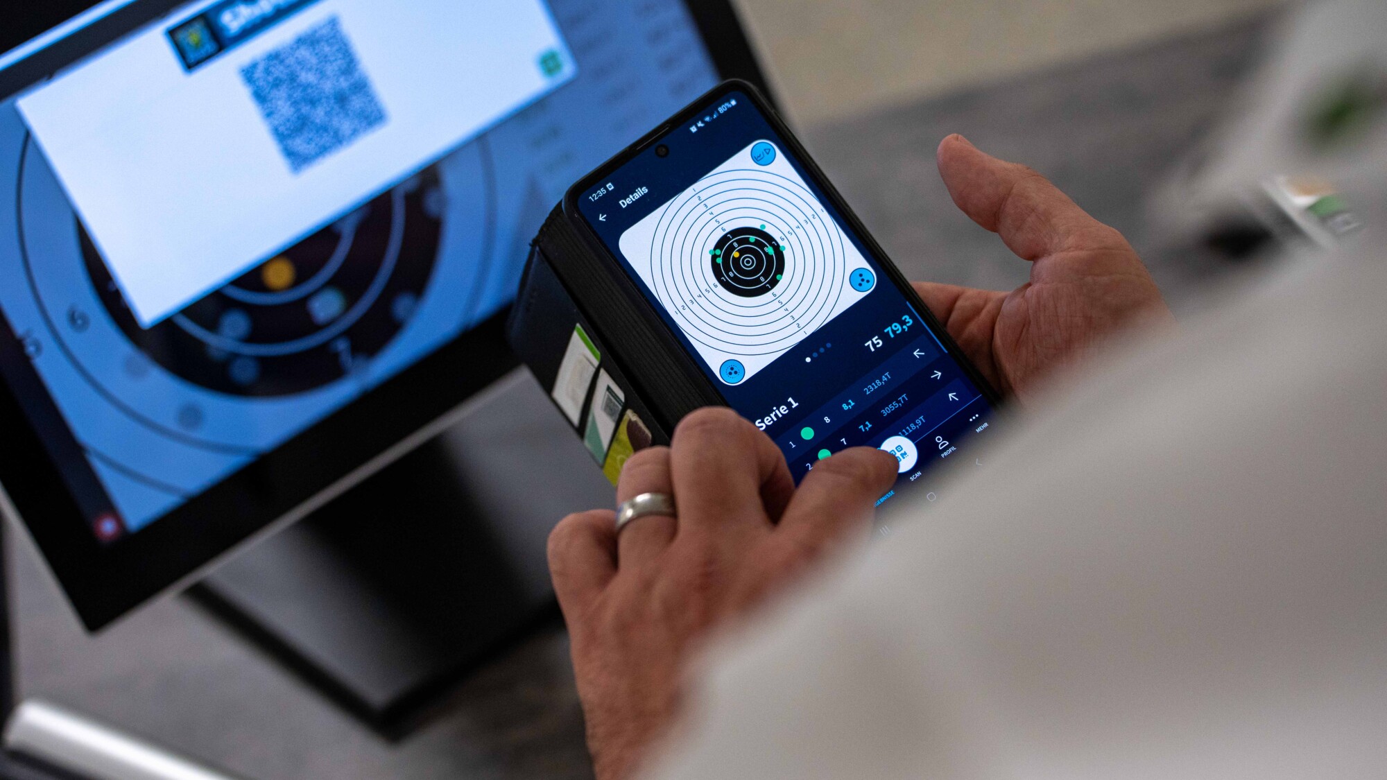 Person nutzt Smartphone-App zur Trefferanzeige auf elektronische Schießscheibe mit digitaler Auswertung in Echtzeit.