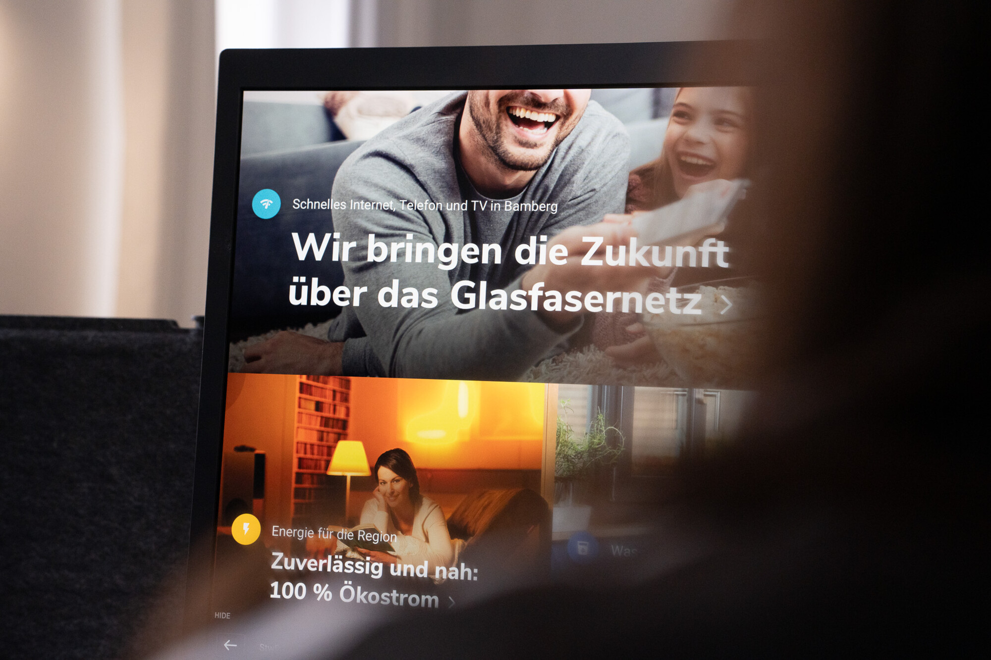 Lächelnde Familie nutzt schnelles Internet und TV über Glasfasernetz, unterstützt durch 100 % Ökostrom für Bamberg.