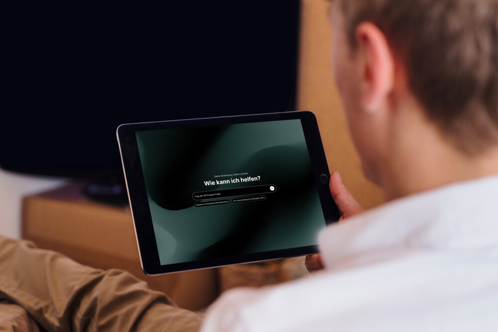 Person nutzt Tablet mit Suchfunktion „Wie kann ich helfen?“ auf Bildschirm, modernes Interface in dunklem Design
